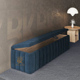 Blue upholstered bench with wooden seat against a textured wall with 'BK' branding.